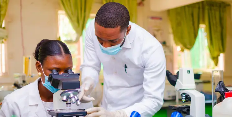 Researchers in a laboratory setting engaged in microscope training, highlighting continuous education in scientific research.