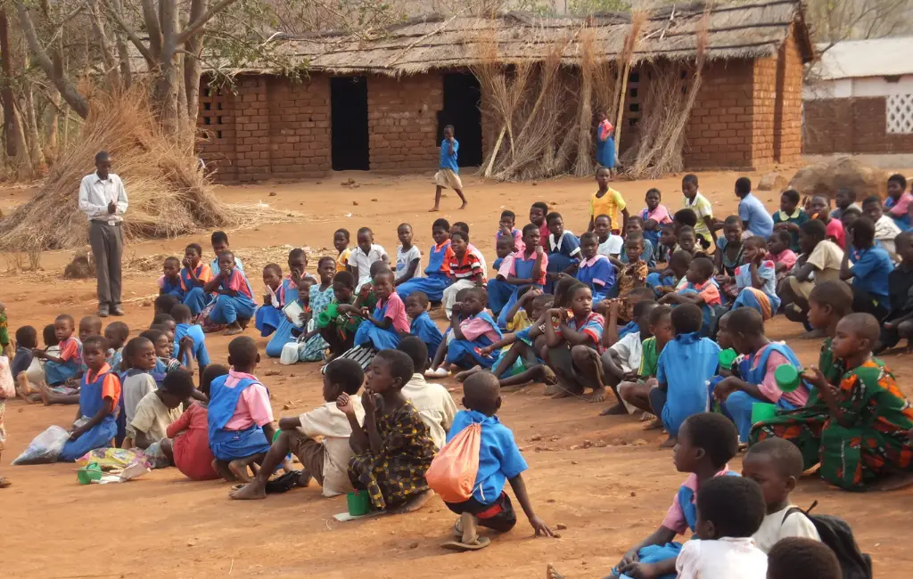 Children gathered outdoors in a rural community school setting, symbolizing education, care, and community development.