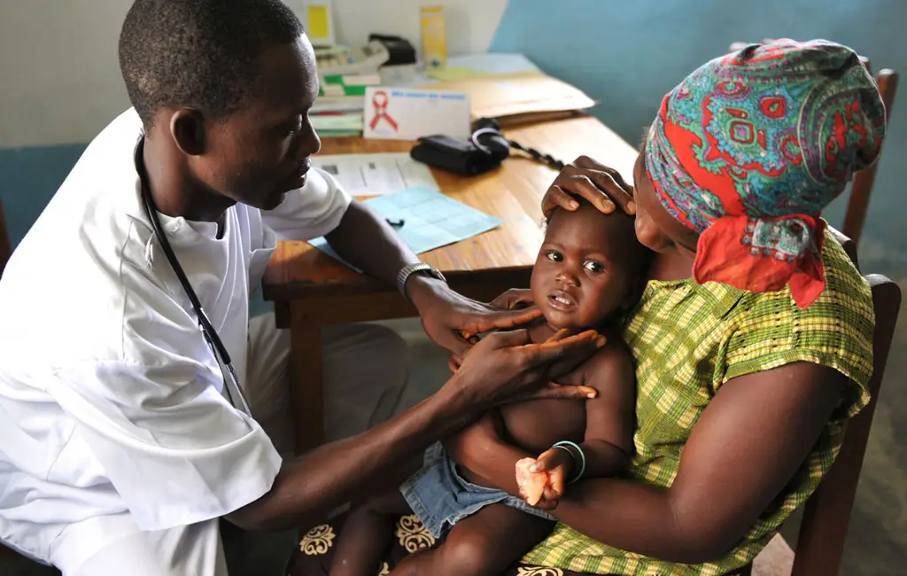 Doctor examining a child held by a mother in a rural healthcare setting, symbolizing compassion, wellness, and community care.